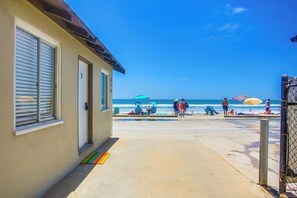 A beachfront property with a covered walkway leading to the beach, a pool area, and a view of the ocean.