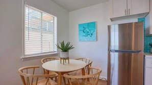 Una cocina moderna con un refrigerador de acero inoxidable, una mesa de comedor de madera y sillas.