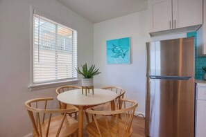 A modern kitchen with a stainless steel refrigerator, wooden dining table, and chairs.
