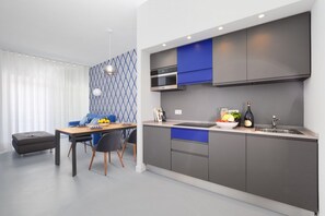 A modern kitchen with grey cabinets, a blue accent wall, and a dining area with a table and chairs.