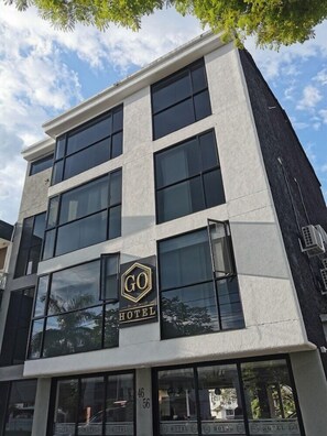 A modern hotel building with a prominent 'GO HOTEL' sign, large windows, and a white facade.