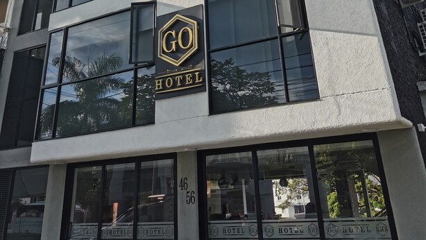 Een modern hotelgebouw met een opvallend 'GO HOTEL' bord, grote ramen en een strakke gevel.