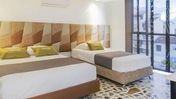 A hotel room with two beds, a patterned headboard, a large window, and a terrazzo floor.