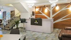 Een hotel receptie met een modern design, inclusief een receptiebalie, zitplaatsen en een trap.