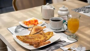 Een ontbijttafel met toast, fruit, koffie en sinaasappelsap.