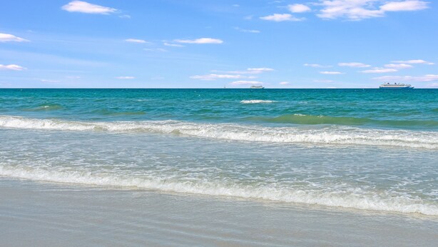 A beach with clear blue water and a ship in the distance. - Sizzling Prices-COOL Summer Retreat (Cocoa Beach)