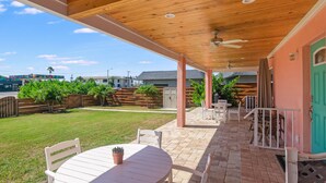 A covered patio area with a table and chairs, a ceiling fan, and a view of the backyard. - Sizzling Prices-COOL Summer Retreat (Cocoa Beach)
