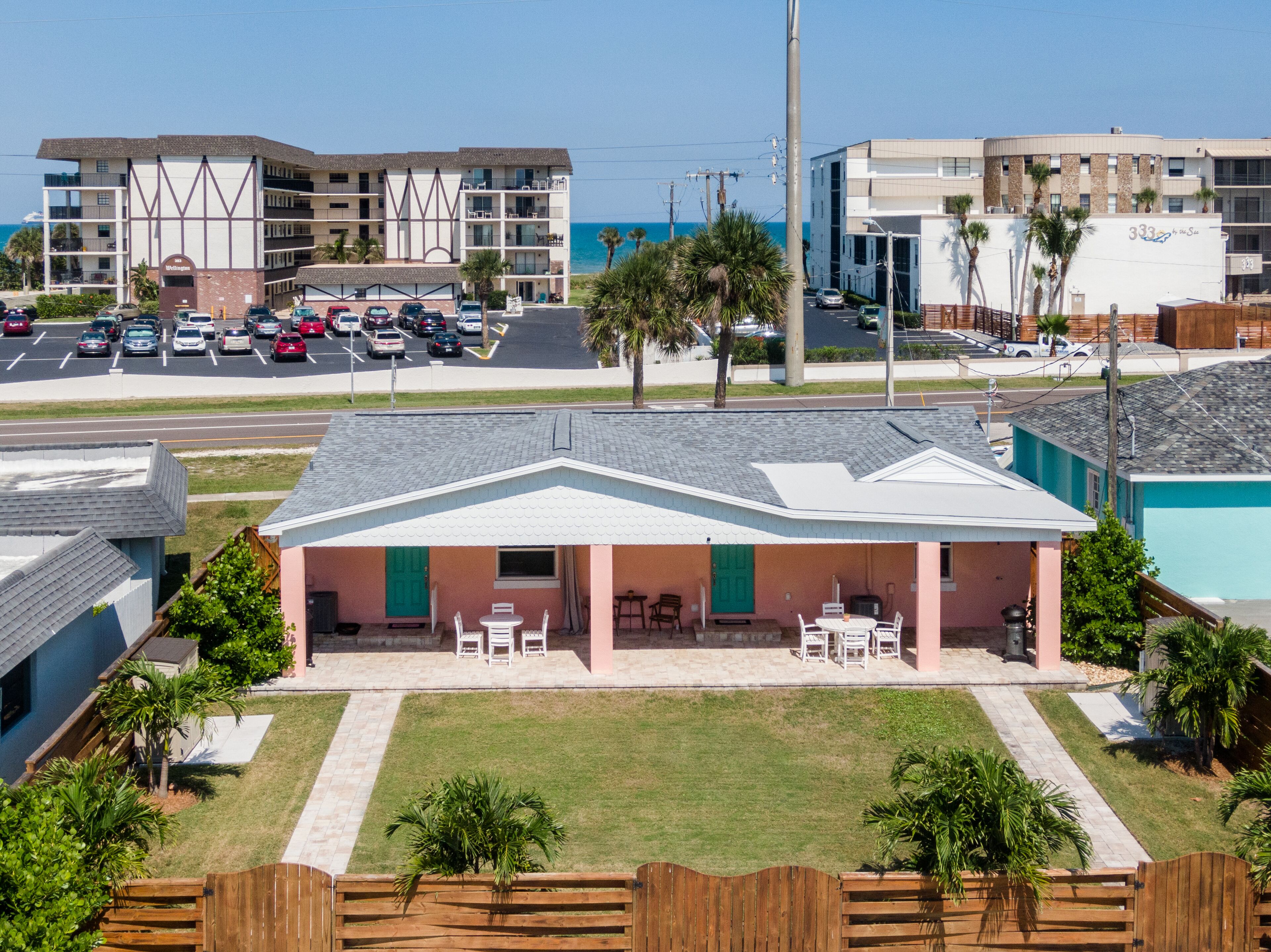 A beachfront hotel with a patio area, a parking lot, and a view of the ocean.