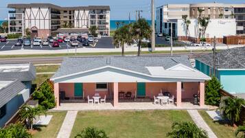A beachfront hotel with a patio area, a parking lot, and a view of the ocean.