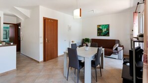 En moderne stue med spiseområde, sofa, fjernsyn og et maleri på væggen.