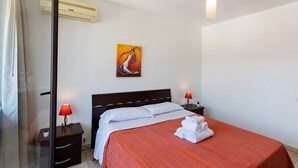 Une chambre d’hôtel comprenant un lit, deux tables de chevet avec des lampes, un tableau au mur et un appareil de climatisation.