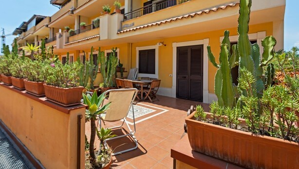 Un immeuble à plusieurs étages doté de balcons, de plantes en pot et de mobilier d’extérieur.