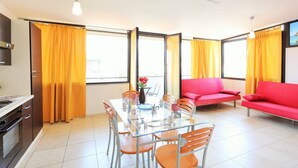 Une cuisine moderne avec une table à manger, des chaises et un canapé rouge.