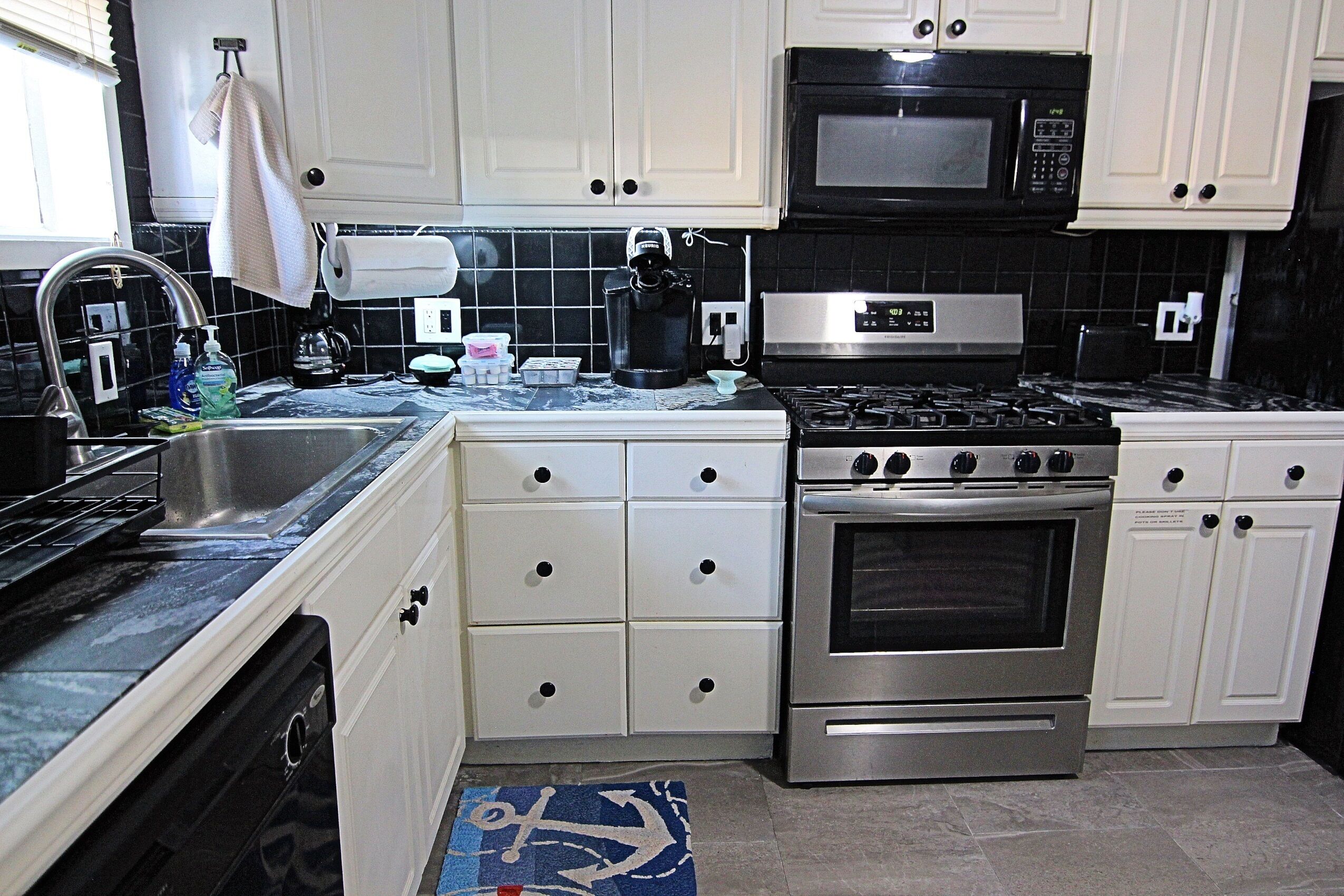 A kitchen with white cabinets, a stainless steel stove, a microwave, and a dishwasher.