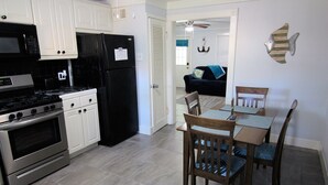 A kitchen with white cabinets, a black refrigerator, stainless steel appliances, and a dining area with wooden chairs and a table. - Galveston Getaway/Cruise, Fishing, Contractors & Beach (Galveston)
