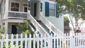 A two-story house with a white picket fence, a front porch, and a staircase leading to the second floor. - Galveston Getaway/Cruise, Fishing, Contractors & Beach (Galveston)