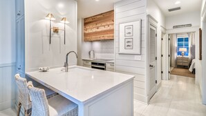 Una cocina moderna con una isla grande, muebles blancos y una pared de acento de madera.