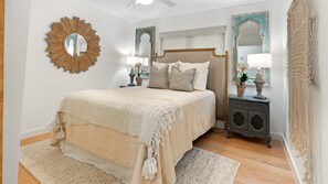 A bedroom with a large bed, two nightstands, a mirror, and a decorative wall piece. - Luxury A-Frame on Lake LBJ, Wakesurf Paradise, Two-Story Dock, Sleeps 16 (Kingsland)