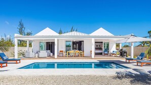 Une maison moderne dotée d’une piscine, d’un espace salon extérieur et d’un patio couvert.
