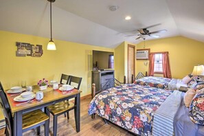 A room with a dining table set for two, a bed with floral bedding, a ceiling fan, and a wall-mounted air conditioner. - Double Retreat · Poconos Nature Escape (Pleasant Mount)