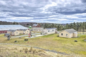 A rural setting with multiple small buildings, including a barn, a house, and a shed, surrounded by a grassy field and trees. - Double Retreat · Poconos Nature Escape (Pleasant Mount)