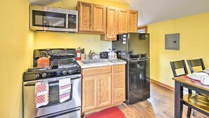 A compact kitchen with wooden cabinets, a stainless steel stove, a microwave, and a refrigerator.