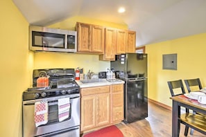 A compact kitchen with wooden cabinets, a stainless steel stove, a microwave, and a refrigerator. - Double Retreat · Poconos Nature Escape (Pleasant Mount)