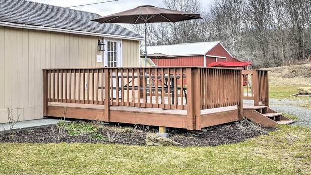 A wooden deck with a railing, a covered patio area, and a small shed in the background.