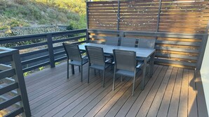 An outdoor deck with a table and chairs, a wooden fence, and a view of the surrounding landscape. - Summer House - Cosy, comfortable, located close to town (Robe)