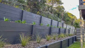 A landscaped garden with tiered wooden planters and a variety of greenery. - Summer House - Cosy, comfortable, located close to town (Robe)
