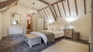 A bedroom with a bed, bedside table, lamp, dresser, and a mirror. - Suncroft - sleeps 8 guests  in 3 bedrooms (Banbury)