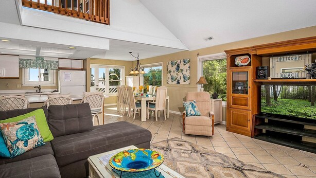 A spacious living room with a high ceiling, a dining area, and a kitchen. - Second Row, 4 Bedroom/3 Bath Home w/ Private Pool and Dock. Sleeps 10 (Holden Beach)