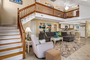 Cozy living area with a high ceiling, sofa, armchairs, and dining area.