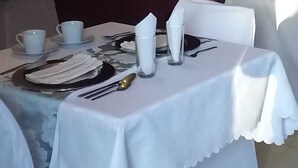 Mesa dispuesta para comer con mantel blanco, platos, cubiertos y servilletas.