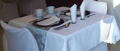 A table set for dining with white tablecloth, plates, cutlery, and napkins.