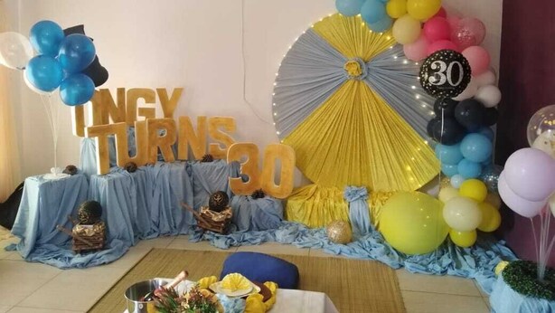 Una habitación decorada con una mesa azul, globos y un cartel que dice 'INGY TURNS 30'.
