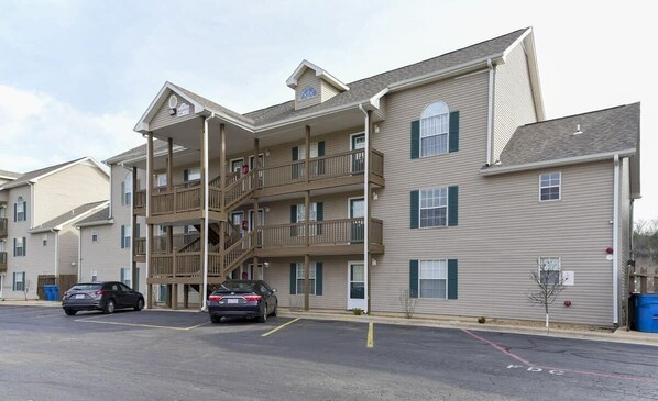A multi-story residential building with a central staircase, balconies, and a parking lot.