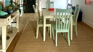 En matplats med ett träpanelat tak, vita väggar och ett matbord omgivet av stolar.