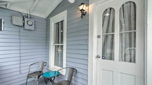 A porch with two metal chairs, a small table, and a white door with a window.