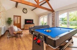 A room with a pool table, a sofa, a television, and a door.
