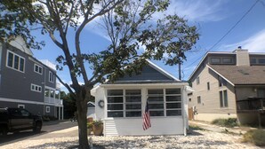 A small house with a porch, a flag, and a tree in front. - Perfect beach cottage for your Lewes vacation! 10 Texas (Lewes)