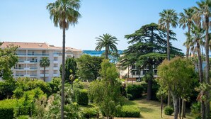 Un hotel con jardín, palmeras y vista al mar.