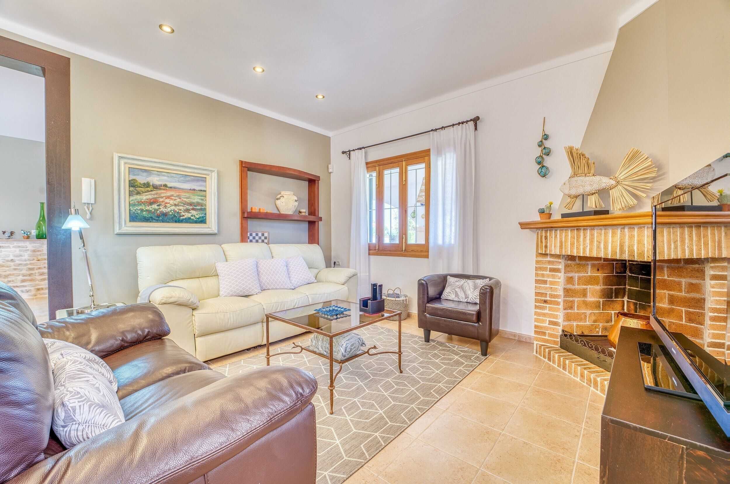 A living room with a fireplace, a sofa, a coffee table, and a painting on the wall.