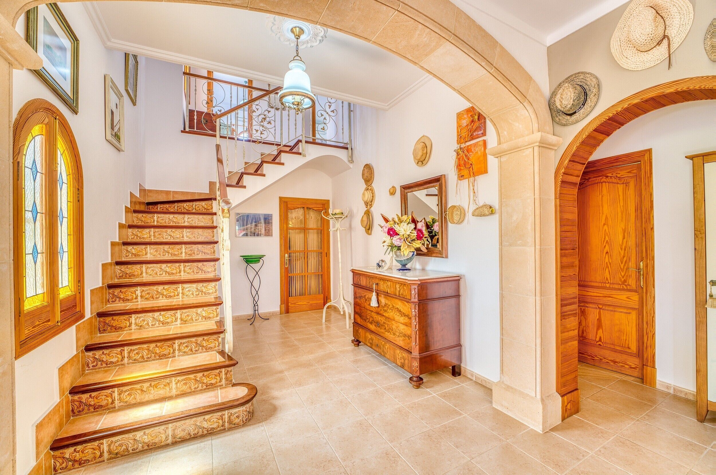 A grand staircase with ornate railings, a wooden door, and a chandelier.
