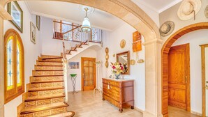 A grand staircase with ornate railings, a wooden door, and a chandelier. - Charming Villa “Finca Santa Eulalia Petit” with Porch and Pool (Can Picafort)