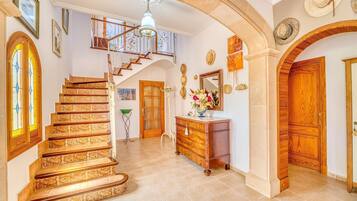 A grand staircase with ornate railings, a wooden door, and a chandelier.