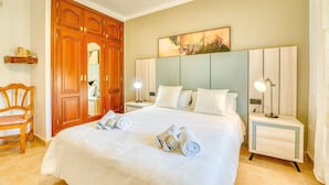 A hotel room with a large bed, wooden wardrobe, bedside tables with lamps, and a painting on the wall. - Charming Villa “Finca Santa Eulalia Petit” with Porch and Pool (Can Picafort)