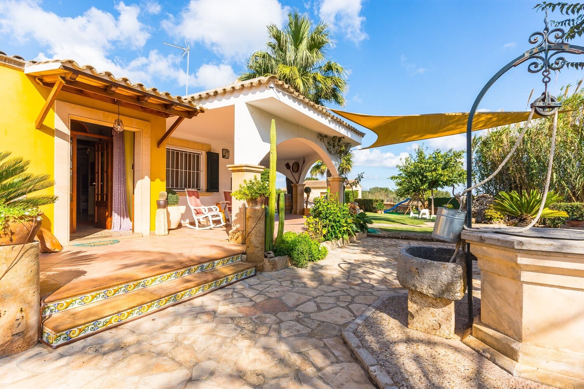 A house with a patio, a swing set, and a garden.
