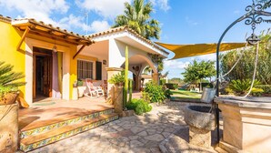 A house with a patio, a swing set, and a garden. - Charming Villa “Finca Santa Eulalia Petit” with Porch and Pool (Can Picafort)