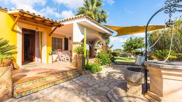 A house with a patio, a swing set, and a garden.
